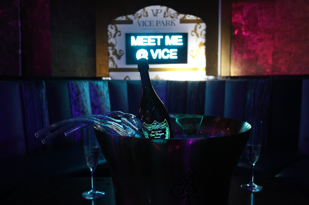 Dom Pérignon bottle in an ice bucket beneath the Vice Park neon sign and MEET ME @ VICE glow