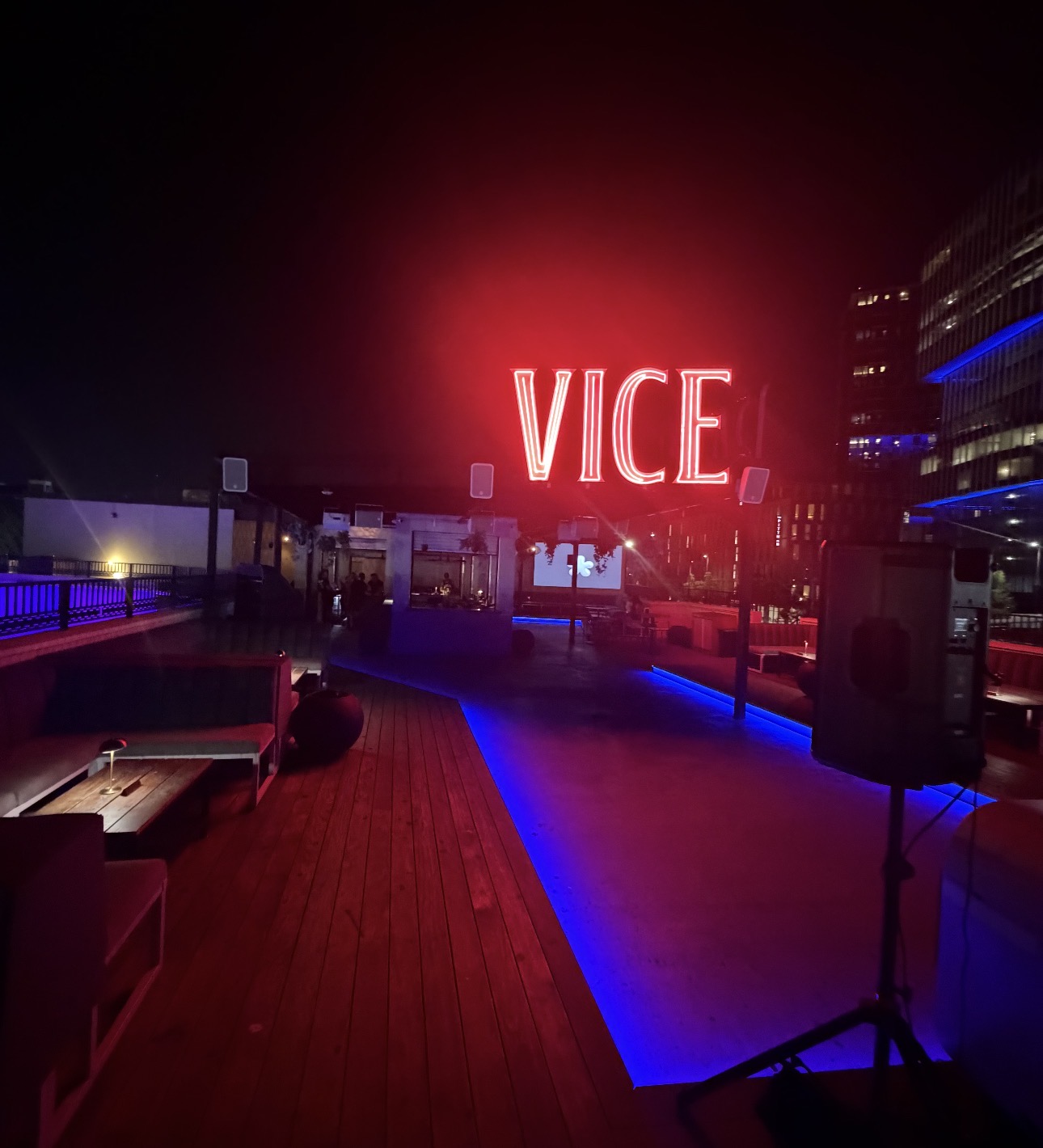 Red VICE neon sign glowing above the open-air rooftop deck with lounge seating and the Dallas skyline at night
