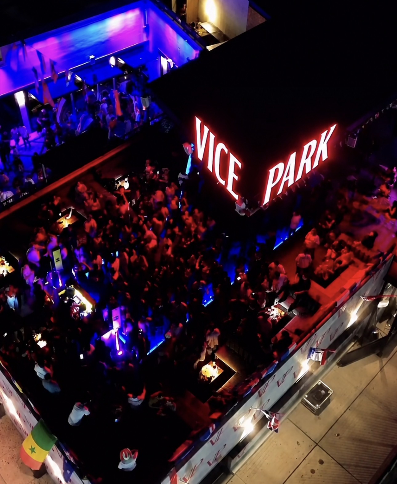 Aerial view of the Vice Park rooftop crowd at night with the illuminated red VICE PARK neon sign glowing above